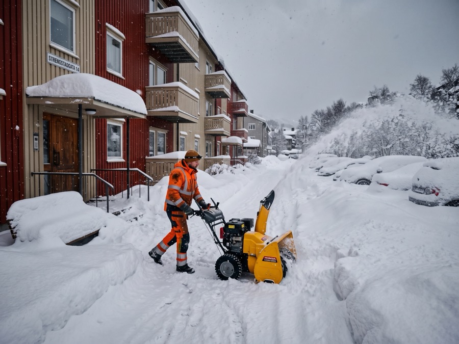 Vaktmester med snøfreser rydder snø foran leilighetsbygg etter kraftig snøfall